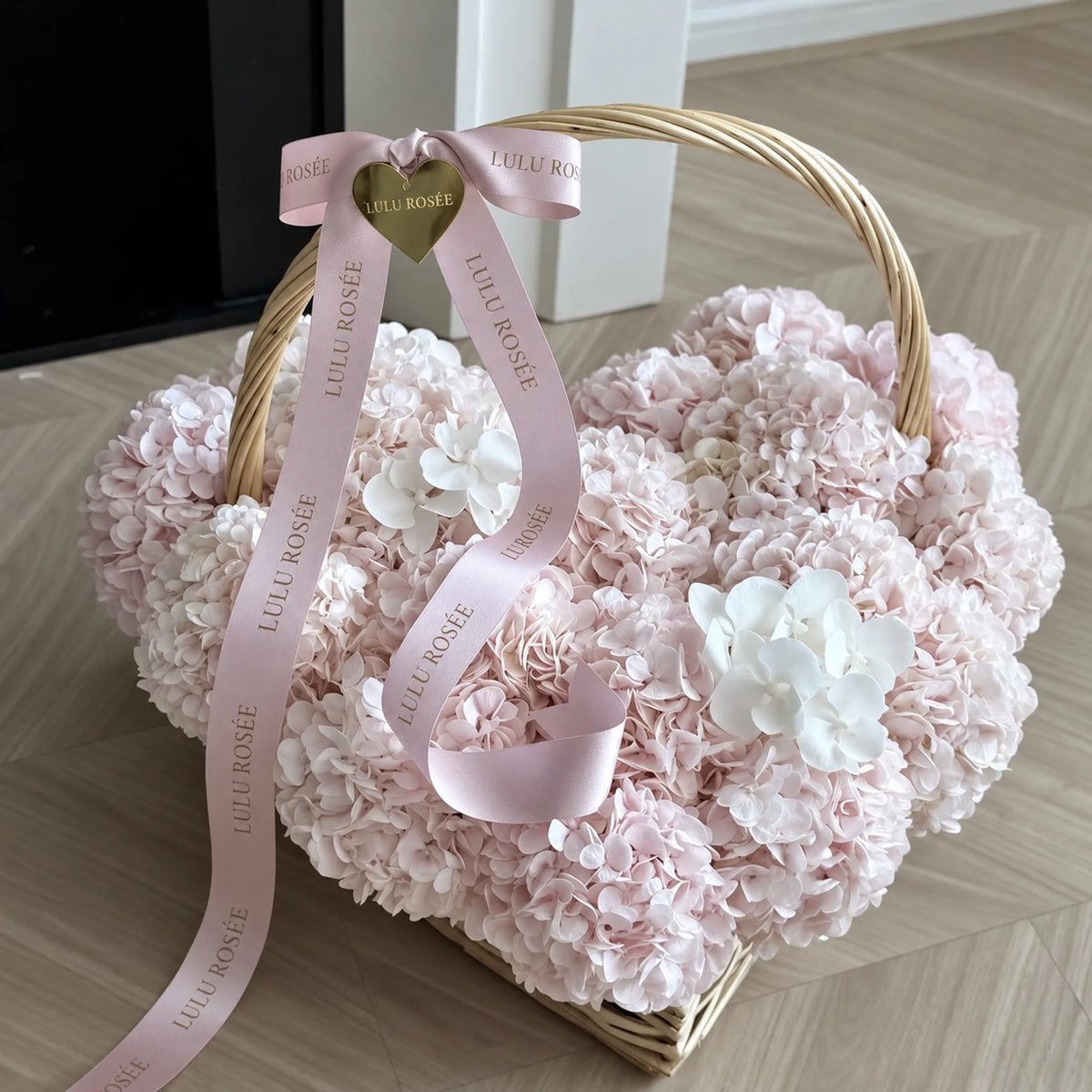 Close view of pale pink preserved hydrangeas and a heart-shaped accent on the basket handle