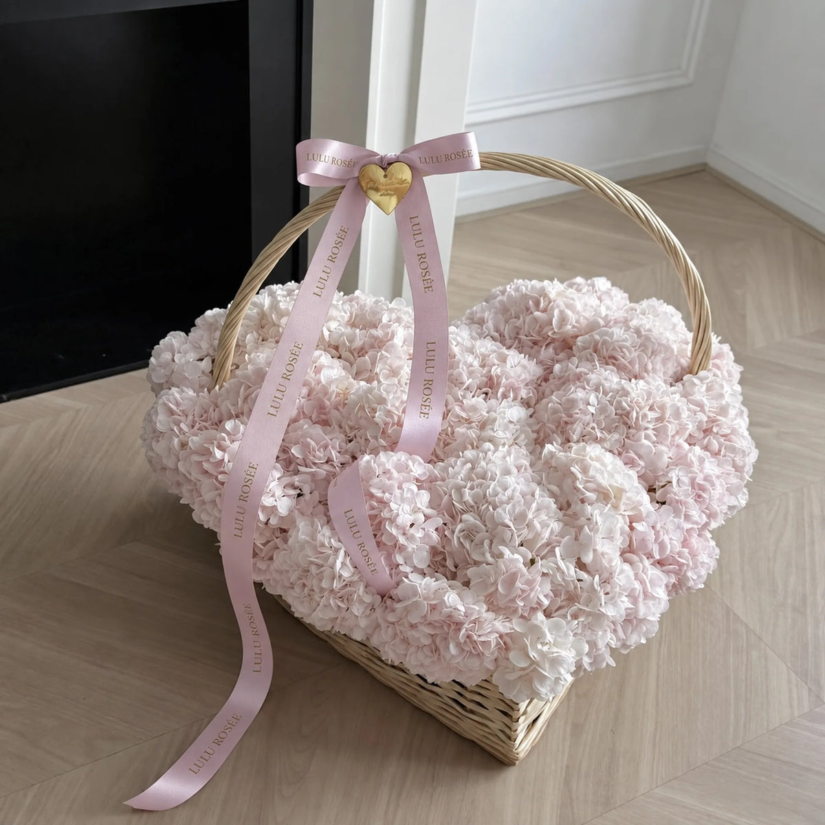 Angled view of a heart-shaped flower basket with a curved handle and pink ribbon