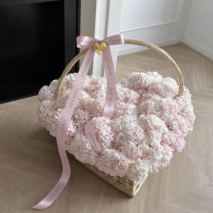 Angled view of a heart-shaped flower basket with a curved handle and pink ribbon