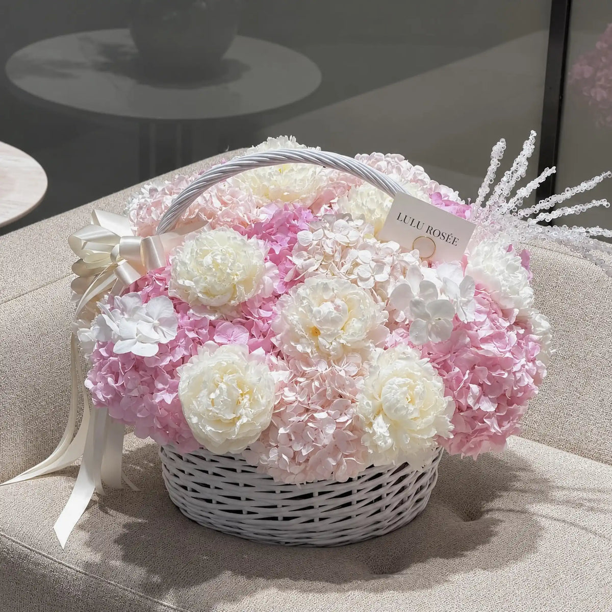 Preserved peony and hydrangea basket in a pink and white palette displayed in an interior