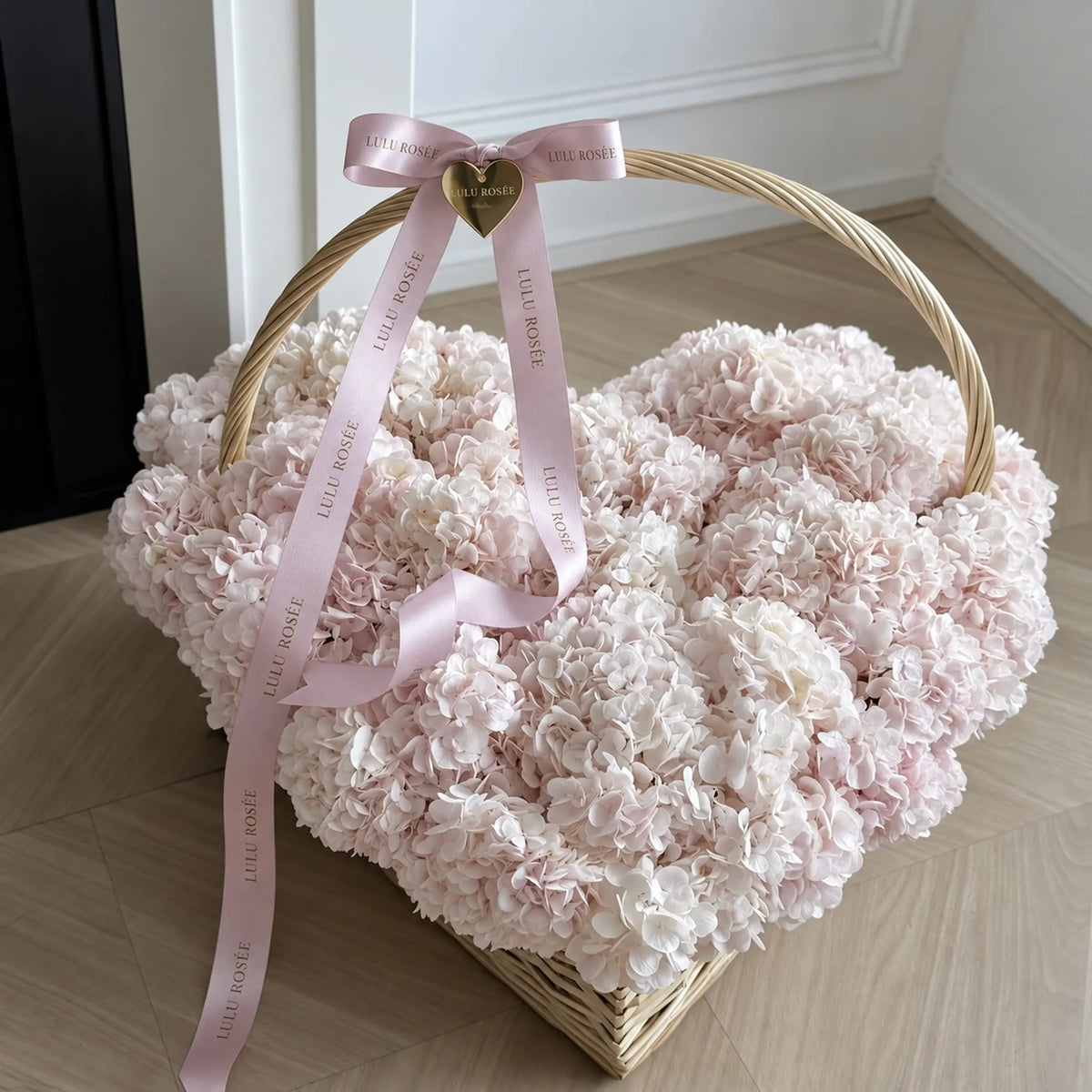 Close view of pale pink preserved hydrangeas in a heart-shaped basket with a curved handle