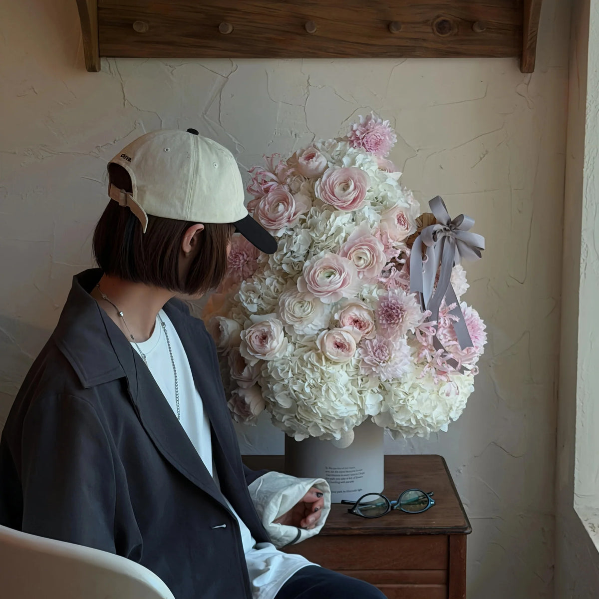 Pink and white preserved flower Christmas tree displayed beside a seated person