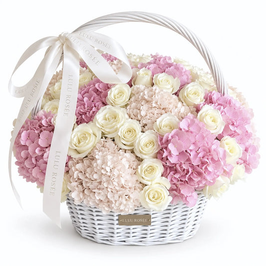 White handled basket of cream preserved roses and pink hydrangeas on a white background