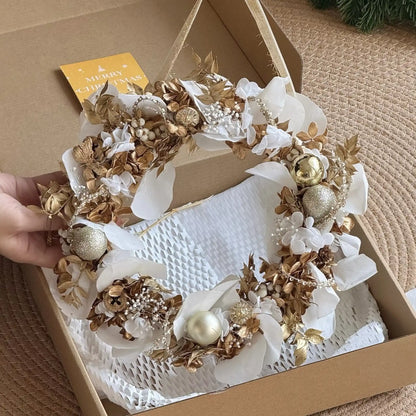 White and gold preserved flower wreath presented in an open gift box with a card.