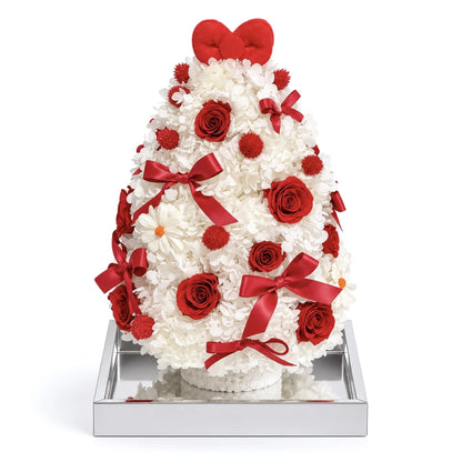 White preserved hydrangea Christmas tree with red roses and ribbon bows on a white background.
