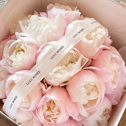 Close view of blush preserved peonies beneath a LULU ROSÉE ribbon